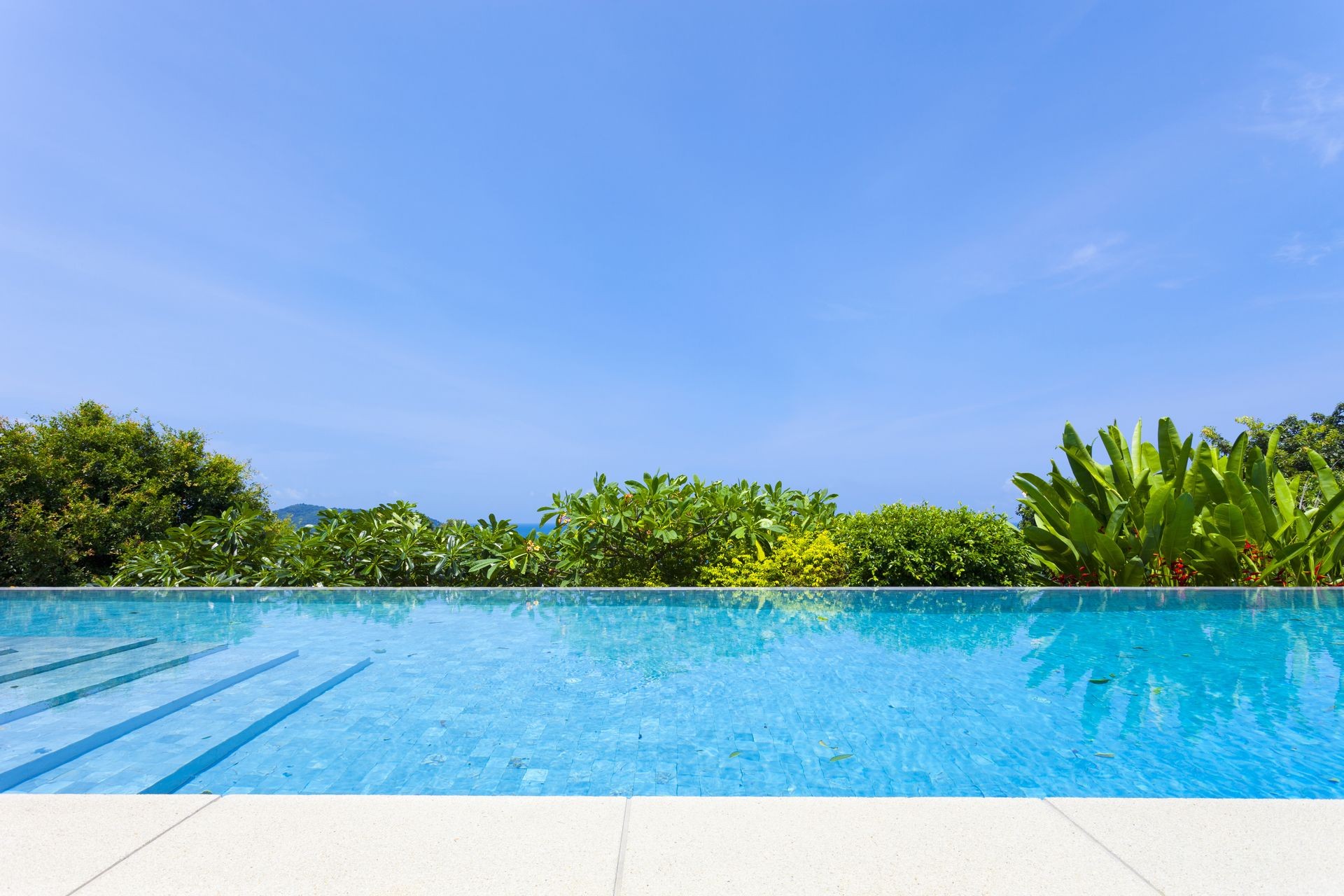 Swimming pool overlooking view andaman sea mountains and blue sky background,summer holiday background concept